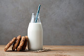 Bottle with milk and chocolate chip cookies on dark background with copy space