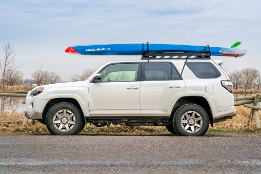 Fort Collins, CO, USA - April 7,2018: A racing stand up paddleboard by Starboard on roof racks of Toyota 4Runner (2016) SUV on a lake shore in one of city natural areas.