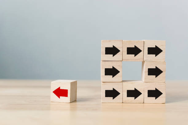 istock Wooden block with red arrow facing the opposite direction black arrows, Unique, think different, individual and standing out from the crowd concept 943916868