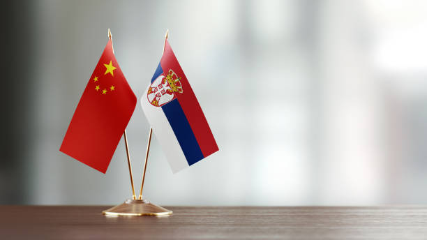 istock Chinese And Serbian Flag Pair On A Desk Over Defocused Background 943916912