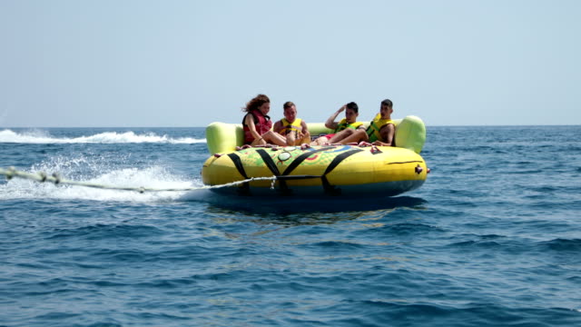 Summer fun.Four friends enjoying an inflatable tube ride at sea