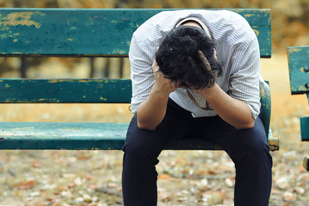 Frustrated stressed Asian business man with hand cover face sitting on the bench of public park and suffering from depression and exhausted Frustrated stressed Asian business man with hand cover face sitting on the bench of public park and suffering from depression and exhausted man crying stock pictures, royalty-free photos & images