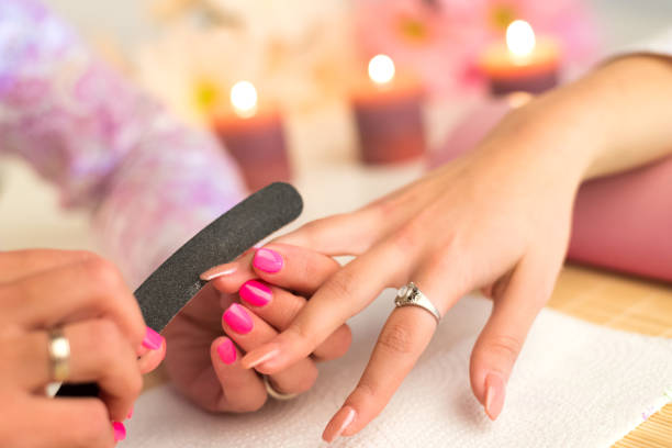 istock Manicurist rasping artificial nails of the customer 943928170