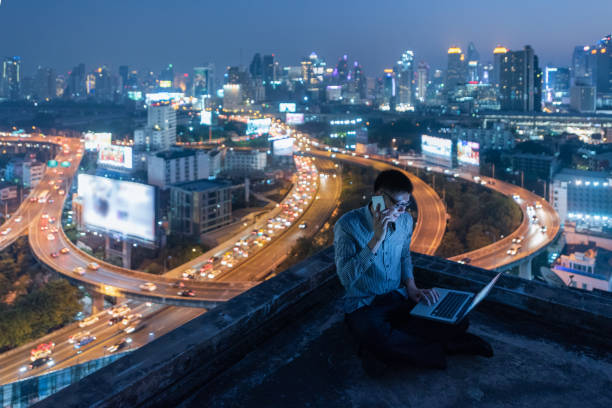 istock Business man work late talking phone on rooftop at night 943928468