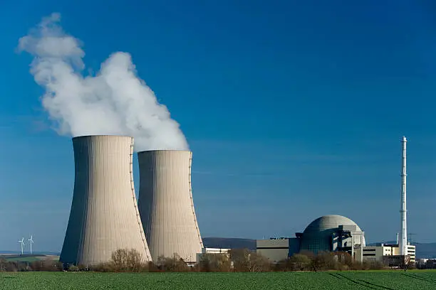 Nuclear power station Grohnde countryside in Lower Saxony, Germany. Two small wind turbines in the Background on the left side of the two cooling towers. Useful as a symbol for the power structure between atomic and alternative energy.