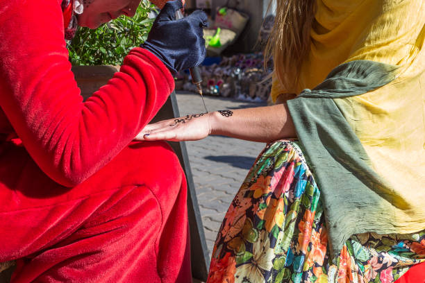istock A woman making temporary henna tattoo on woman's hand. 943943442
