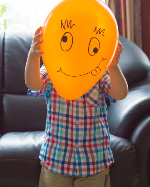 istock Little boy with an orange balloon smiley face 943948714