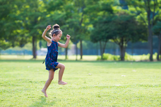 petites filles jouant sur la pelouse - sautiller photos et images de collection