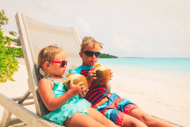 istock little boy and girl drinking coconut on beach 943978664