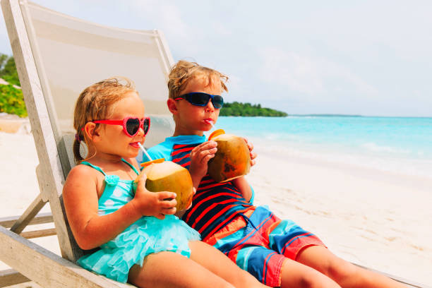 istock little boy and girl drinking coconut on beach 943978686