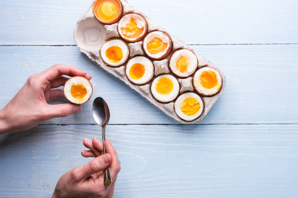uova sode in mano su uno sfondo di legno - hard cooked egg foto e immagini stock