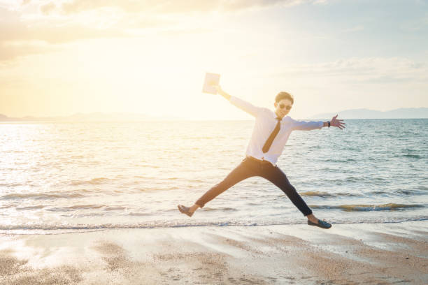 istock Relaxing Businessman using  laptop and smartphone on the beach 943986108