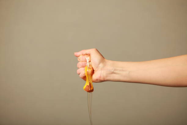 raw chicken egg crushed in the hand drains yolk stock photo