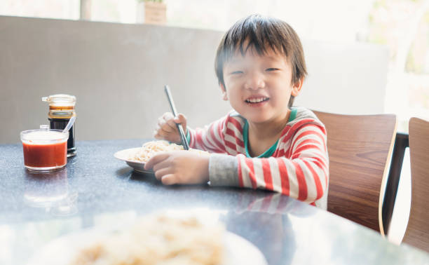 istock Asian child eating delicious noodle with chopstick 943999208