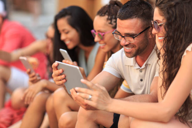istock Young people sitting on street and using smart phones 944004360