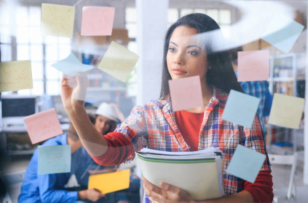 istock Asian woman taking post-it notes from glass wall 944004438