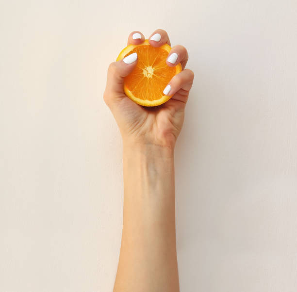 female hand squeezing orange. vitamin c concept in minimal style. - vitamin a letter a food orange imagens e fotografias de stock