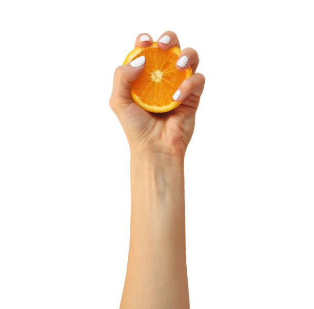 istock A female hand squeezing half an orange, isolated on white. 944015438