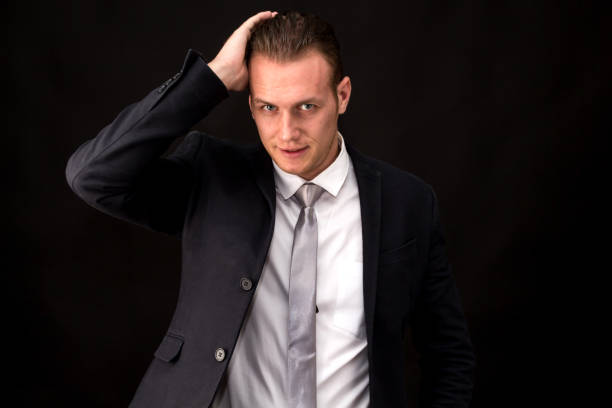 istock Businessman in black suit standing isolated on black background 944019800