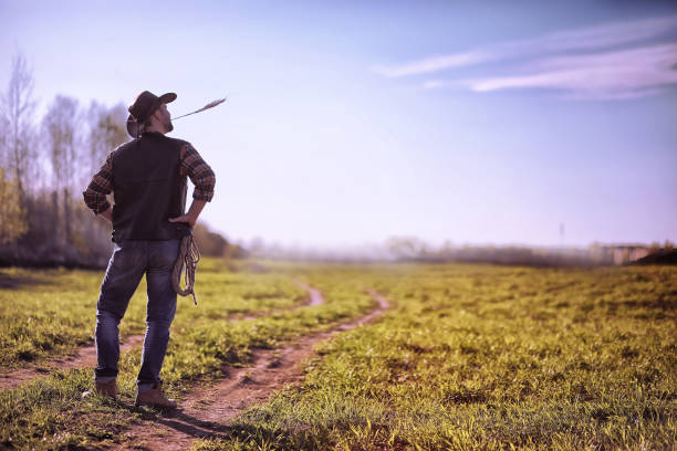 istock Cowboy standing in a field at sunset 944022198