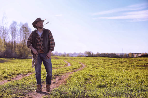 istock Cowboy standing in a field at sunset 944022266