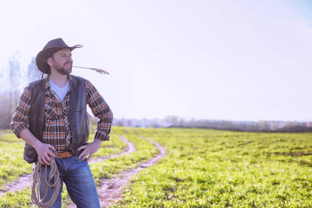 istock Cowboy standing in a field at sunset 944022300