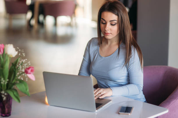 istock brunette woman working on her laptop at a restaurant 944031402