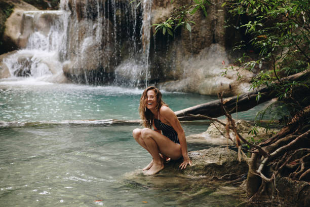 mujer sentada en un estanque natural - waterfall thailand tropical rainforest tropical climate fotografías e imágenes de stock