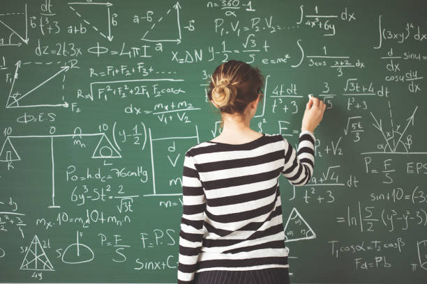 joven estudiante escribiendo con tiza en la pizarra verde en aula - matemáticas fotografías e imágenes de stock