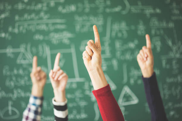 istock Students raised up fingers green chalk board in classroom 944039966