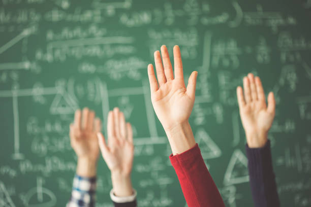 estudiantes levantados las manos pizarra verde en aula - símbolo matemático fotografías e imágenes de stock