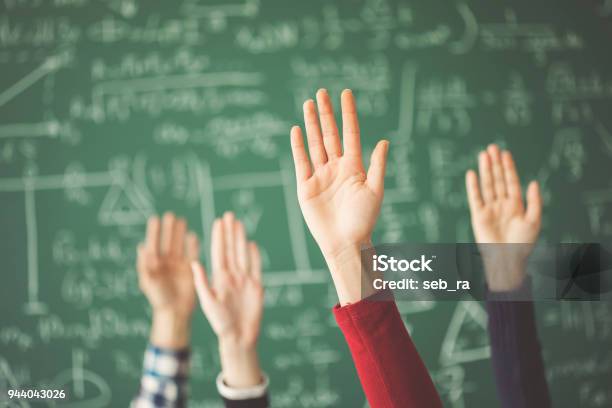Students Raised Up Hands Green Chalk Board In Classroom Stock Photo - Download Image Now