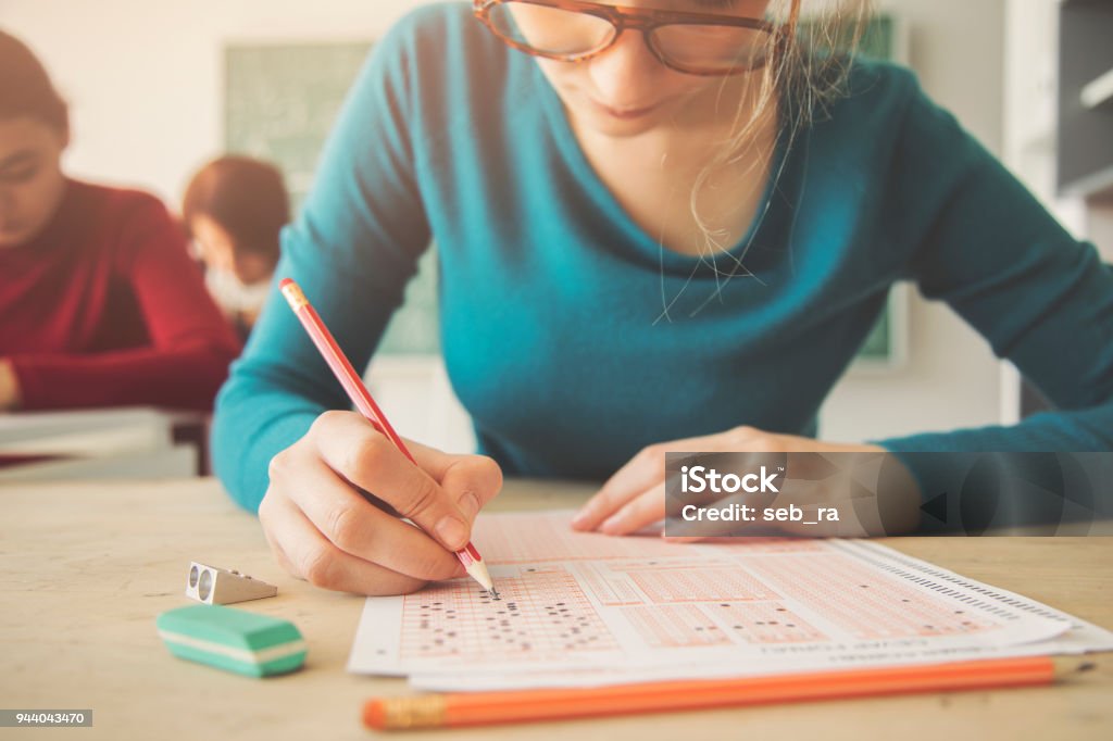 Giovane studentessa che ha un esame in classe - Foto stock royalty-free di Esame