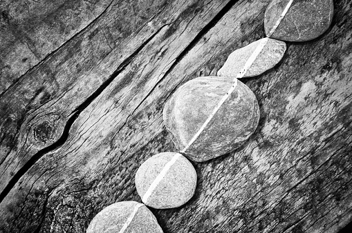 Row of stones on a wooden background, black and white