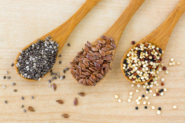 Dried Chia seed, Linseed flaxseed, Quinoa seed tri-color blend on wooden spoon, wood background