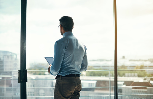 Rearview shot of a mature businessman looking out the window in an office
