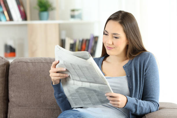 istock Woman reading a newspaper sitting on a couch 944064542