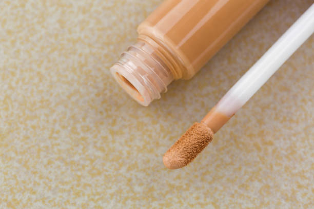 Doe-foot applicator next to tube of creamy concealer, high cover to conceal spots, blemishes Doe-foot applicator next to tube of creamy concealer, high cover to conceal spots, blemishes, on yellow tile background concealer stock pictures, royalty-free photos & images