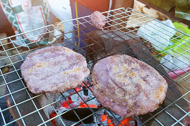 local traditional northern thai food called Kao Ji - flat dough made from sticky rice or riceberrry on grill on hot charcoal photo taken from above top view