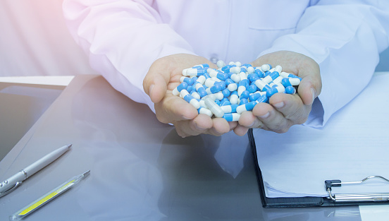 Healthcare and medical concept . Doctor in uniform holding white and blue capsule pill in office at hospital,Selective focus