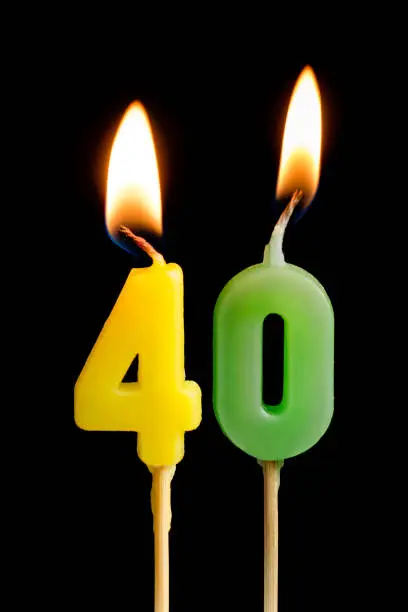 Burning candles in the form of forty figures (numbers, dates) for cake isolated on black background. The concept of celebrating a birthday, anniversary, important date, holiday, table setting