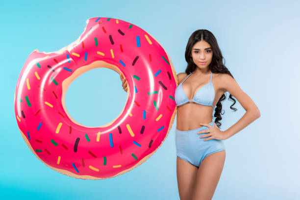 istock attractive girl posing with inflatable donut ring, isolated on blue 944077528