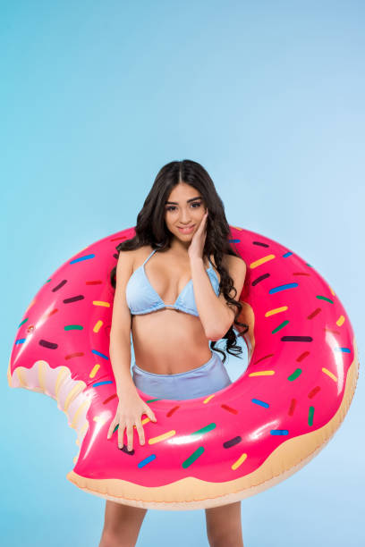 istock slim pretty girl posing with inflatable donut ring, isolated on blue 944080146