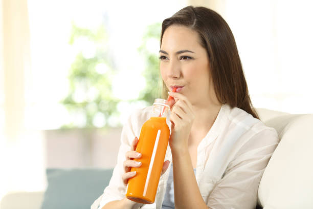 istock Woman drinking orange juice with a straw 944081090
