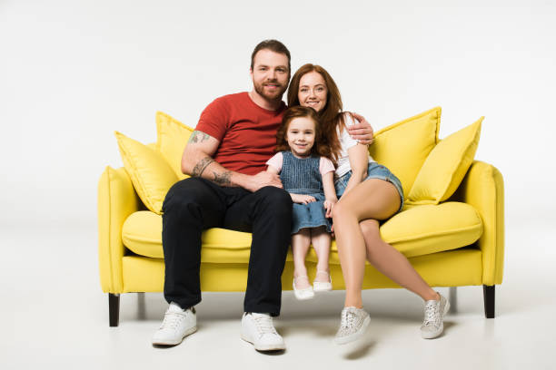 istock Little child between mother and father on couch isolated on white 944085188