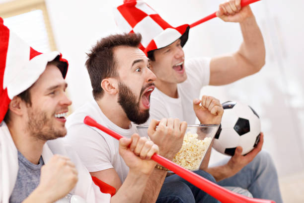 happy male friends cheering and watching sports on tv - fan sport football male imagens e fotografias de stock