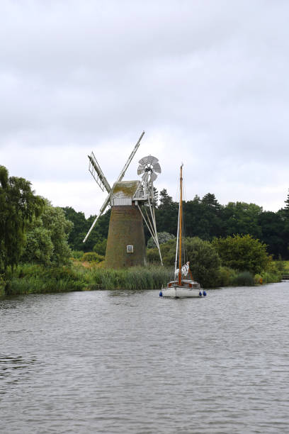 A series of sailing boats photographed on a sunny day on the Norfolk Broads in Norfolk, England.