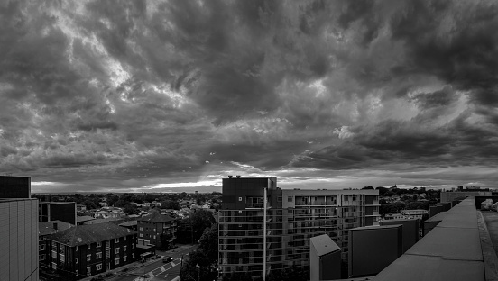 Sydney, Australia - Oct 25, 2017: City skyline with a rapidly approaching storm. Features a dramatic sky. Viewed from building rooftop in late afternoon. Image in monochrome.
