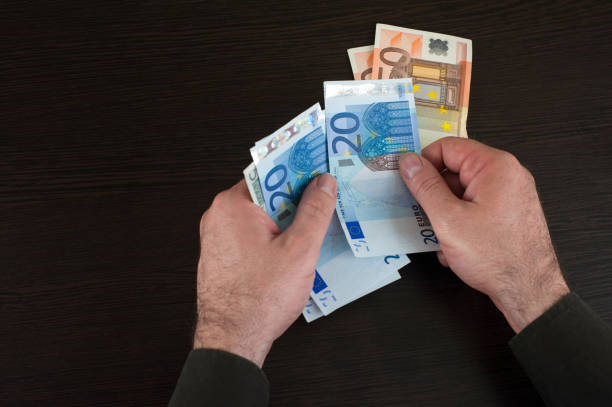 istock Hands counting euro banknotes on dark wooden surface 944096928
