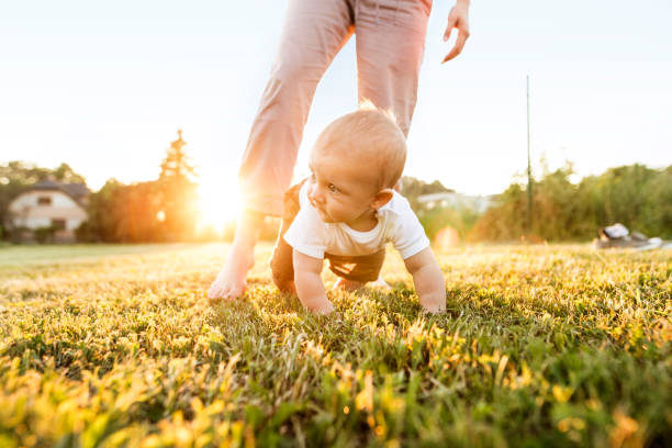 istock Baby boy with unrecognizable mother crawling outside. 944098608